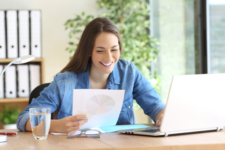 Caucasion woman in a blue blouse looking at a pie chart and her lap top comparing features of ATS