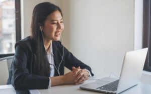 candidate wearing earbuds answering remote hybrid interview questions on a laptop