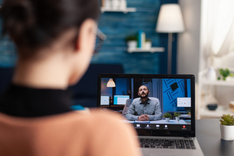 Virtual live interview conversation between two people with one shown on a laptop screen
